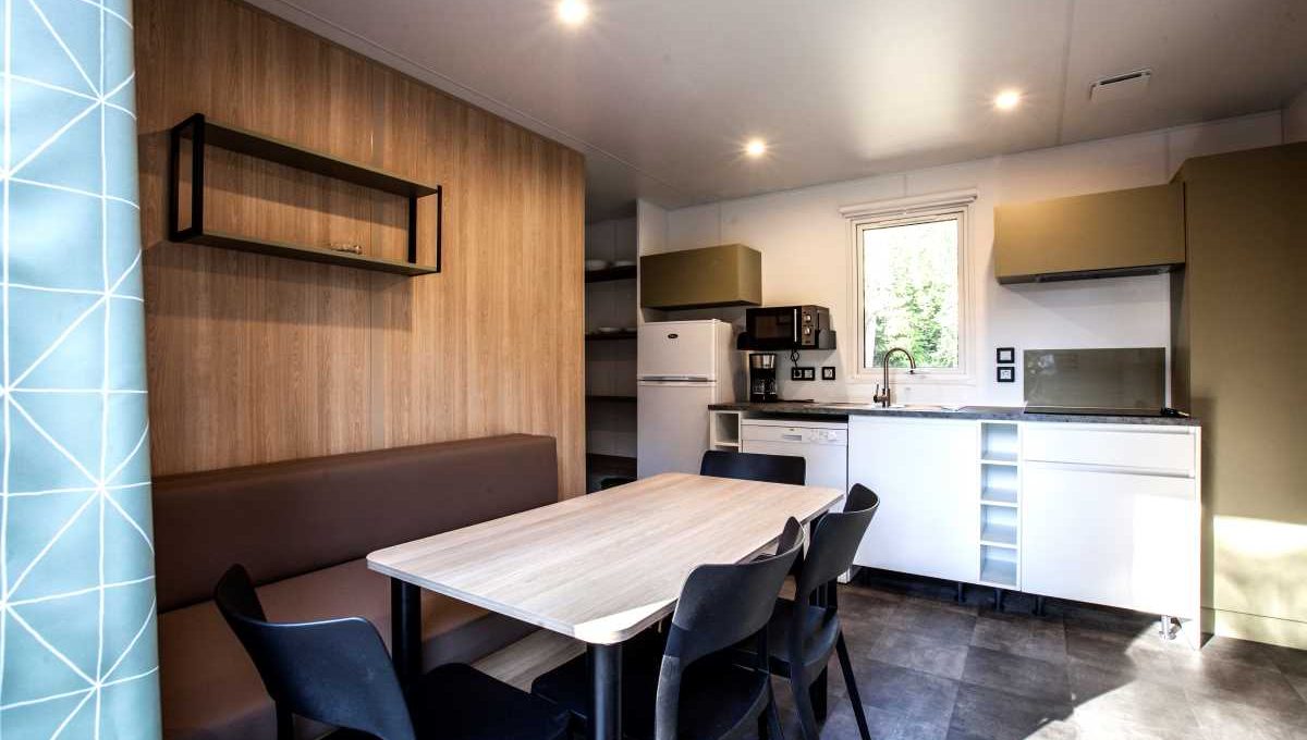 Intérieur de mobil-home avec cuisine équipée et espace repas au camping du lac d’Aydat en Auvergne